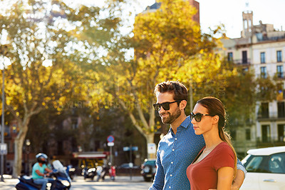 Buy stock photo Shot of an affectionate young couple walking together in the city