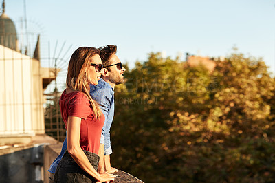 Buy stock photo Shot of a smiling young couple leaning on a balcony in the city looking at the view