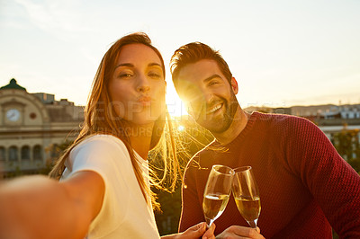 Buy stock photo Shot of a smiling couple drinking champagne and taking a selfie together while standing together on a balcony