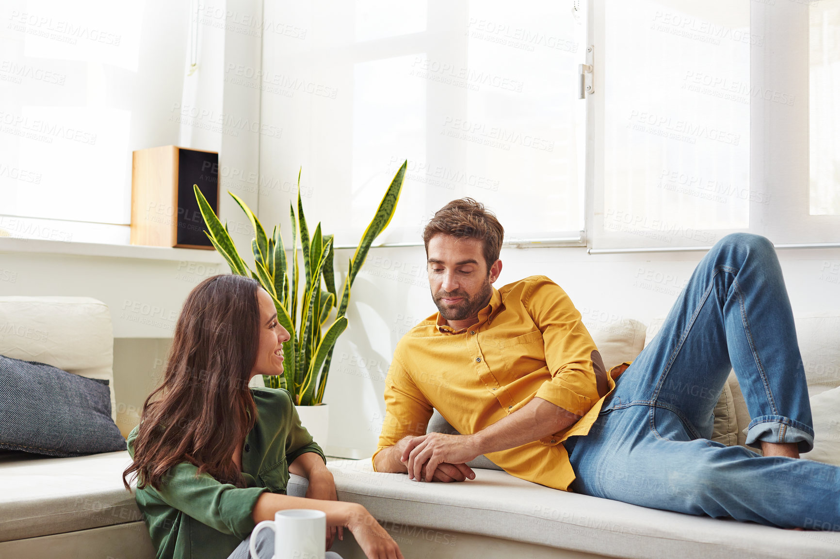 Buy stock photo Shot of a smiling young couple talking together while relaxing in their living room