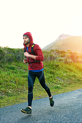 Buy stock photo Shot of a focused young man out for a run on a cool morning