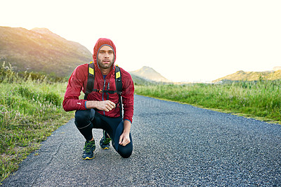Buy stock photo Shot of a focused young man crouching while preparing for a run on a cool morning