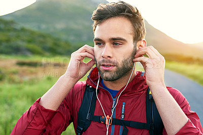 Buy stock photo Shot of a focused young man putting on headphones while preparing for a morning run