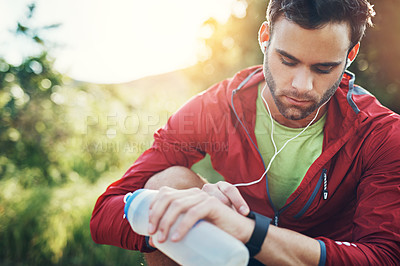 Buy stock photo Shot of a young drinking water and checking his watch while out for a run