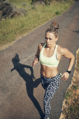 Buy stock photo Shot of a focused young woman out for a run in the early morning