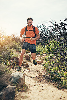 Buy stock photo Shot of a focused young man running alone outside on a trail
