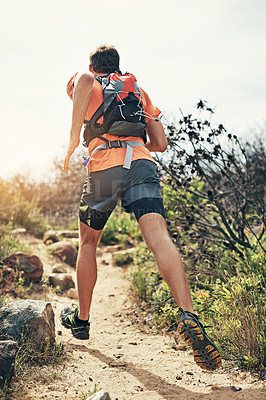 Buy stock photo Rearview shot of a young man running alone outside on a trail