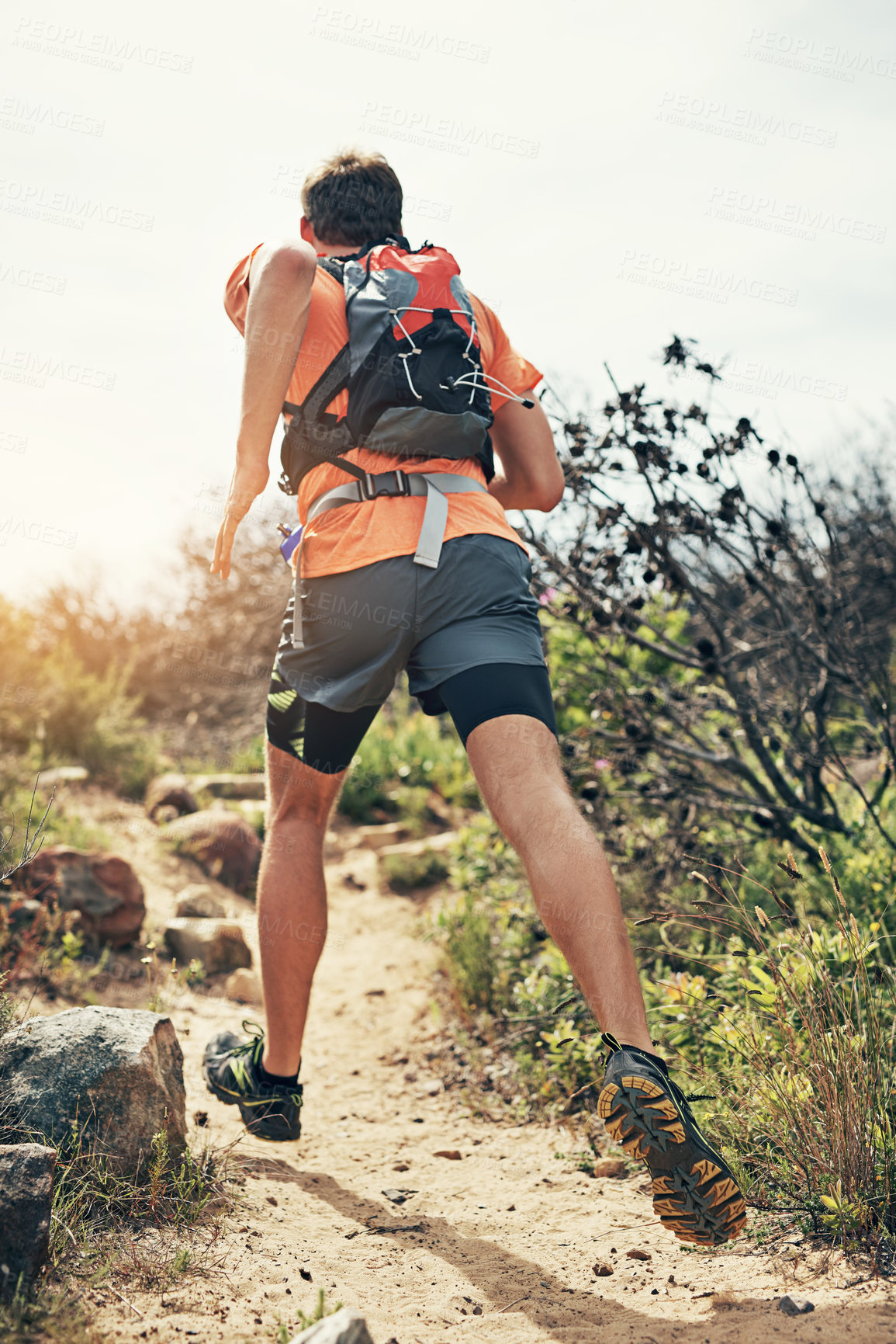 Buy stock photo Rearview shot of a young man running alone outside on a trail