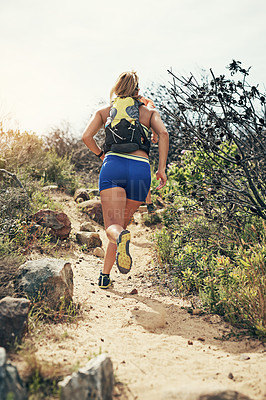 Buy stock photo Rearview shot of a young man running alone outside on a trail