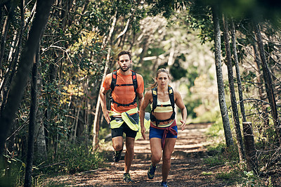 Buy stock photo Shot of two young friends running together along a trail in a forest