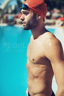 Buy stock photo Shot of an athletic young man in swimwear standing by a pool