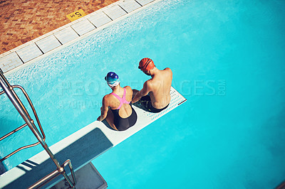 Buy stock photo High angle shot of two swimmers sitting on a diving board above a swimming pool