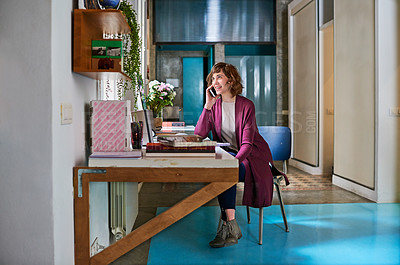 Buy stock photo Shot of a young woman talking on a cellphone at her computer in her home office