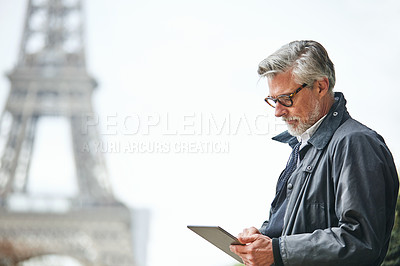 Buy stock photo Shot of a handsome mature man using a digital tablet in Paris with the Eiffel Tower in the background