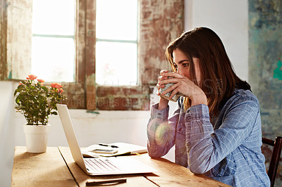 Buy stock photo Shot of a young woman drinking a coffee while sitting at a desk in her room using a computer