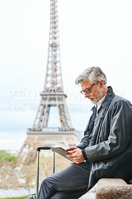 Buy stock photo Shot of a handsome mature man using a digital tablet in Paris with the Eiffel Tower in the background