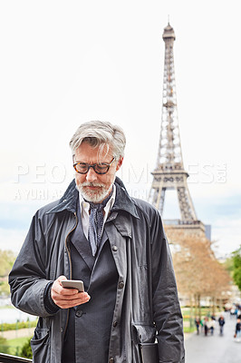 Buy stock photo Shot of a handsome mature man using a cellphone in Paris with the Eiffel Tower in the background