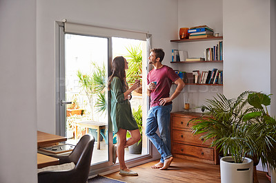 Buy stock photo Shot of a smiling young couple standing together in their living room drinking coffee
