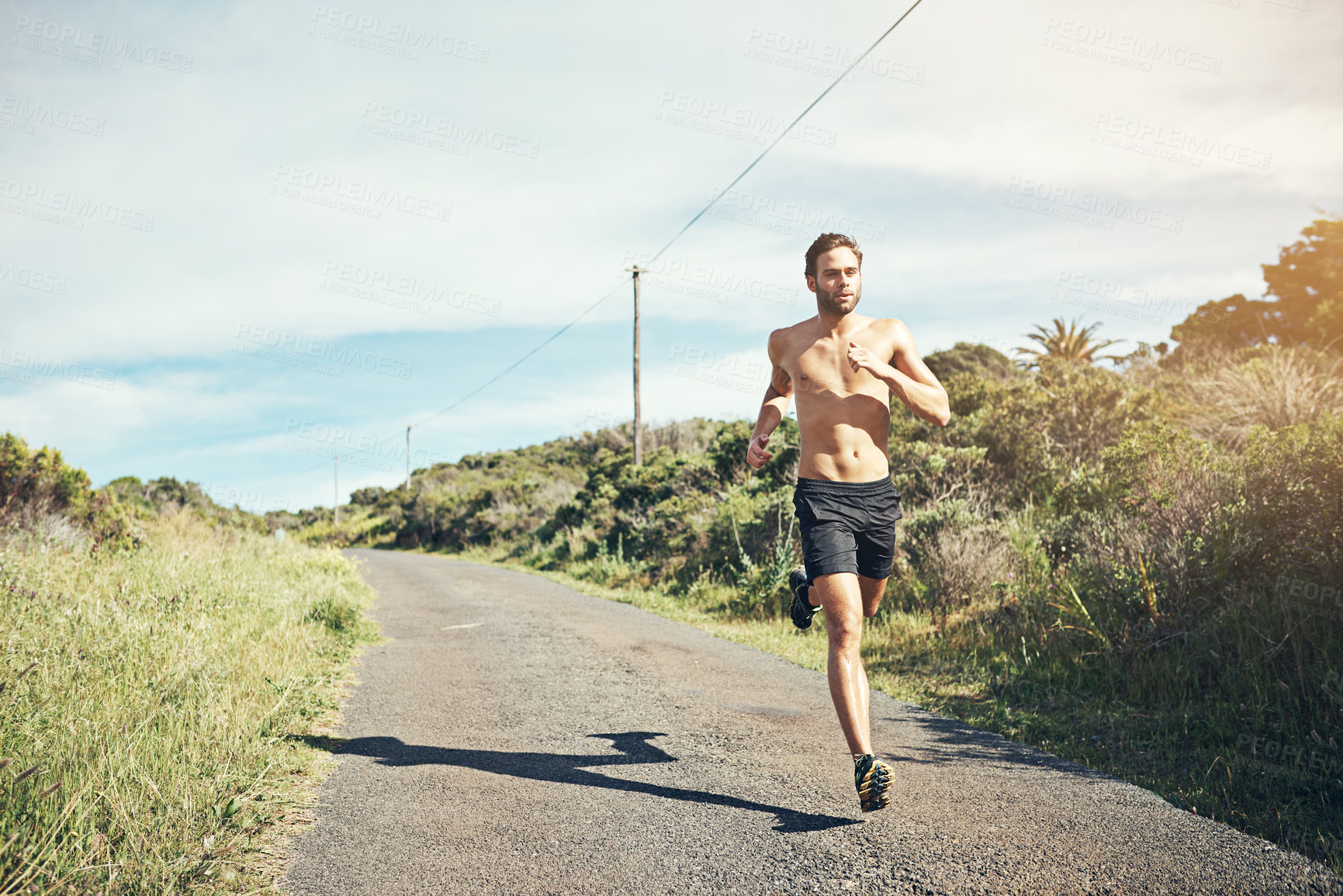 Buy stock photo Shot of a bare chested young man out for an early morning run