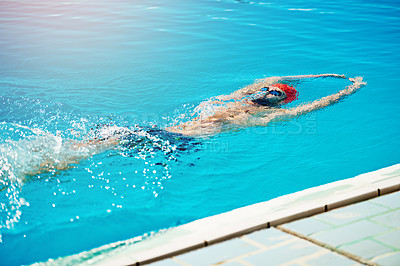 Buy stock photo Shot of a handsome young male swimmer doing backstroke in a swimming pool