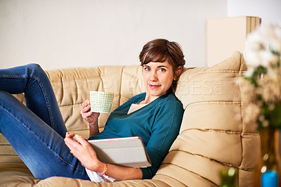 Buy stock photo Shot of an attractive young woman chilling on the sofa with her tablet