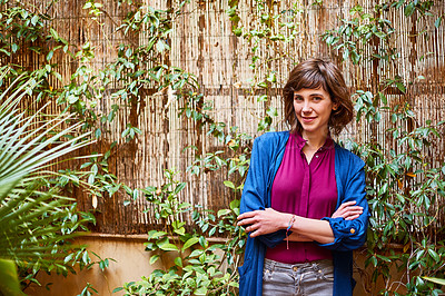 Buy stock photo Shot of an attractive young woman standing with her arms folded in the garden