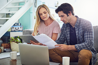 Buy stock photo Shot of an affectionate young couple looking over some paperwork at home