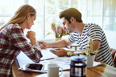 Buy stock photo Shot of an affectionate young couple looking over some paperwork at home
