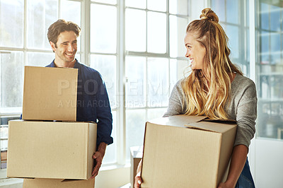 Buy stock photo Shot of a young couple carrying boxes while moving house