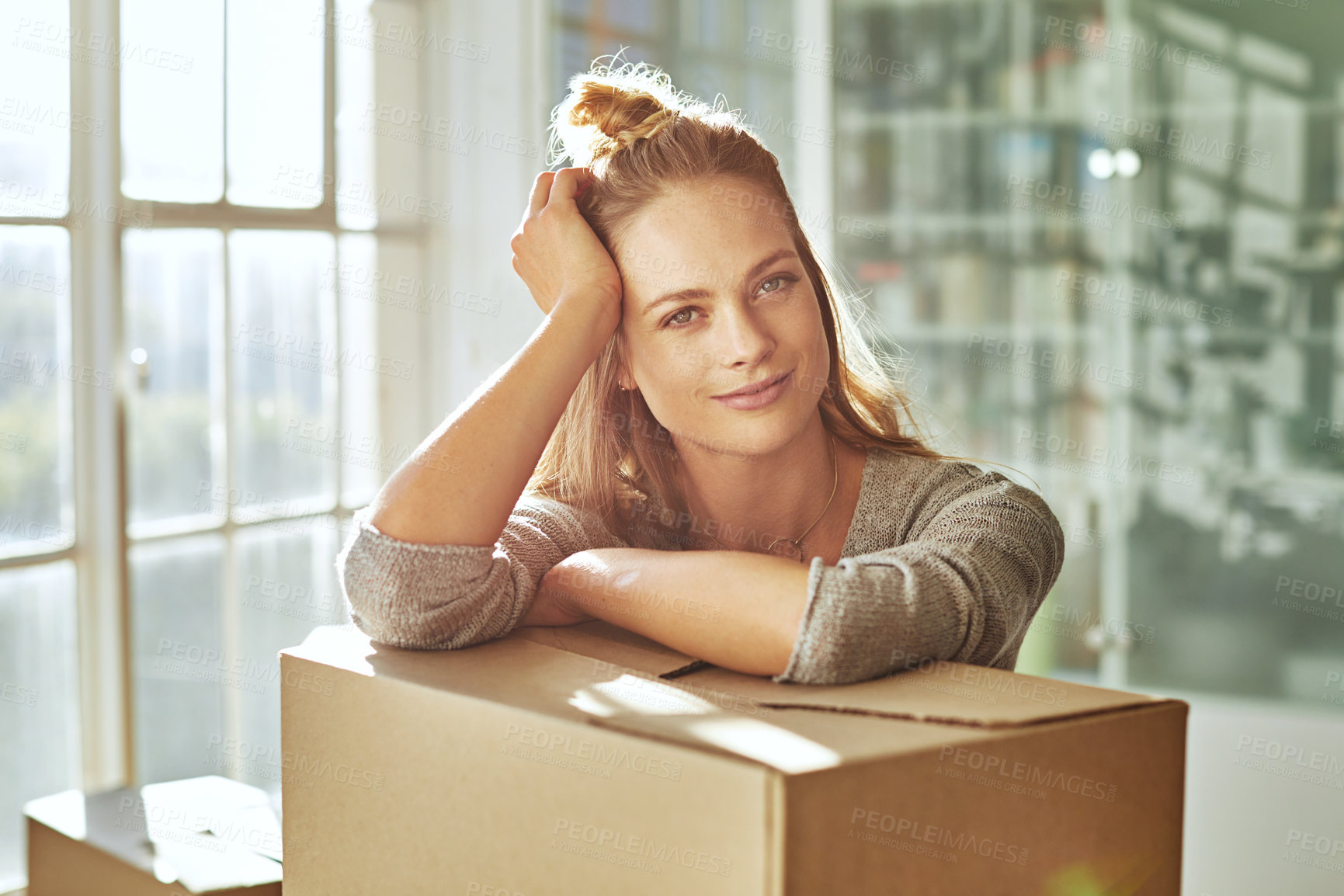 Buy stock photo Shot of a beautiful young woman leaning on a box while moving house