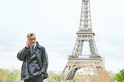 Buy stock photo Shot of a handsome mature man talking on a cellphone in Paris with the Eiffel Tower in the background