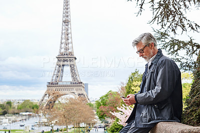 Buy stock photo Shot of a handsome mature man using a cellphone in Paris with the Eiffel Tower in the background