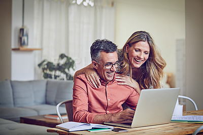 Buy stock photo Shot of a mature woman leaning on her husband while he works on his laptop