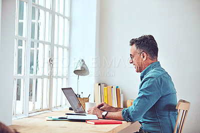 Buy stock photo Shot of a handsome and mature man working on his laptop at home