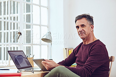 Buy stock photo Shot of a handsome and mature man working on his laptop at home