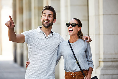 Buy stock photo Shot of an affectionate young couple walking together in the city