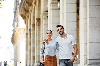 Buy stock photo Shot of an affectionate young couple walking together in the city