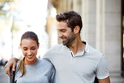 Buy stock photo Shot of an affectionate young couple walking together in the city