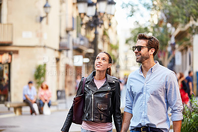 Buy stock photo Shot of an affectionate young couple walking together in the city