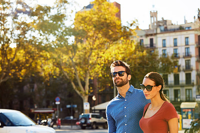 Buy stock photo Shot of an affectionate young couple walking together in the city