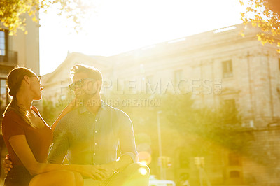 Buy stock photo Shot of a affectionate young couple sitting on a rooftop together at sunset