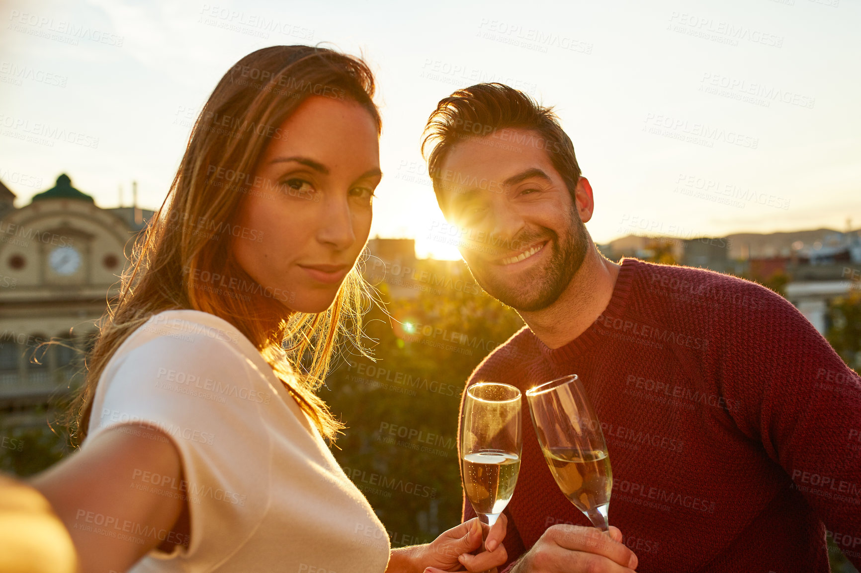 Buy stock photo Shot of a smiling couple drinking champagne and taking a selfie together while standing together on a balcony