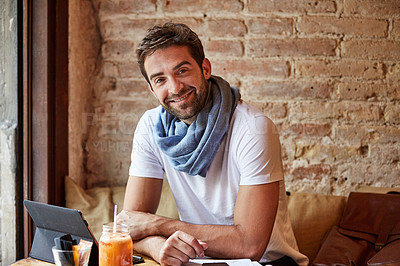 Buy stock photo Portrait of a handsome young man using his digital tablet while sitting in a cafe