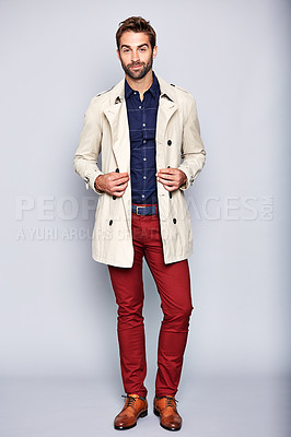 Buy stock photo Studio portrait of a handsome young man posing in a trench coat against a grey background