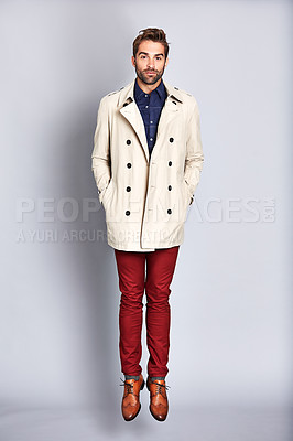 Buy stock photo Studio portrait of a handsome young man posing in a trench coat against a grey background