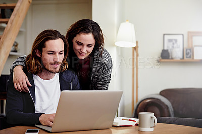 Buy stock photo Shot of an attractive young woman watching her husband as he works from home