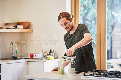 Buy stock photo Shot of a handsome young man preparing coffee in the kitchen at home