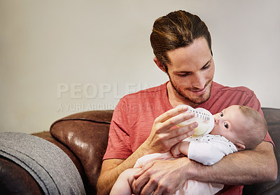 Buy stock photo Shot of a handsome young man feeding his newborn baby girl on the sofa at home