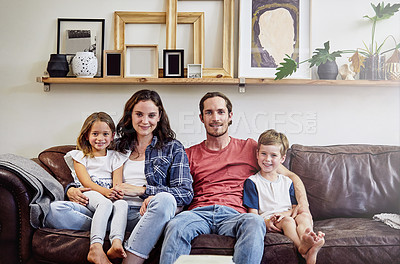 Buy stock photo Portrait of a happy young family sitting on their sofa at home