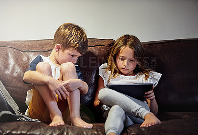 Buy stock photo Shot of a young girl reading to her brother while sitting on a sofa at home